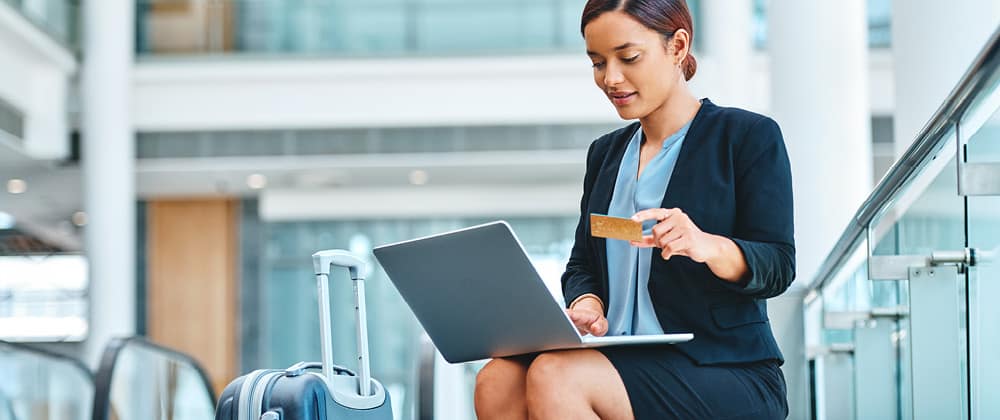 Woman using a laptop and holding a financial card