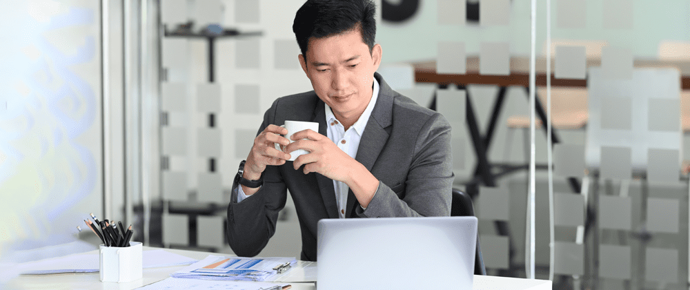 Man holding a mug and looking at a laptop