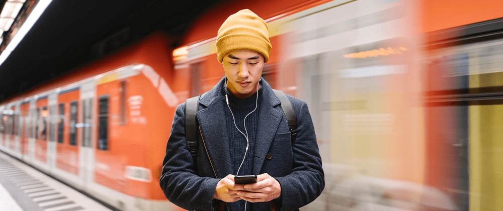 Man using a phone in front of a train