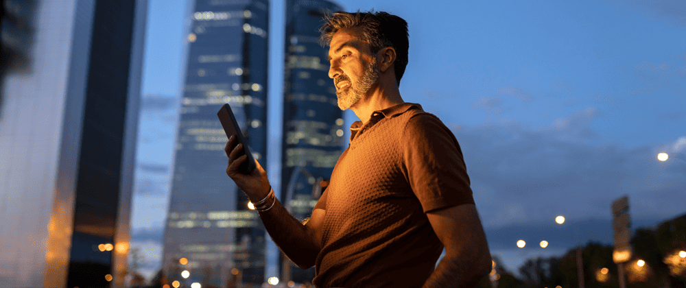 Man using a phone in front of a skyline