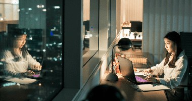 femme devant un ordinateur portable avec reflet dans la fenêtre