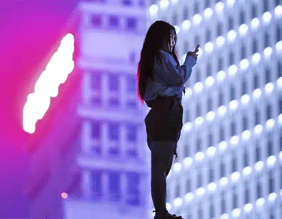 Frau schaut vor einem hohen Gebäude auf ein Handy