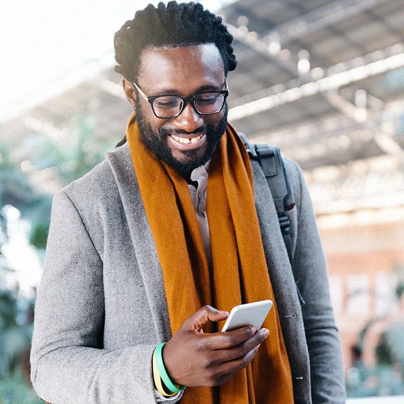 улыбающийся мужчина смотрит в экран мобильного телефона
