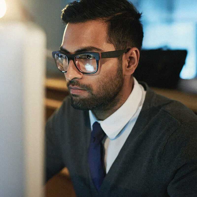 homme avec des lunettes regardant un écran d’ordinateur