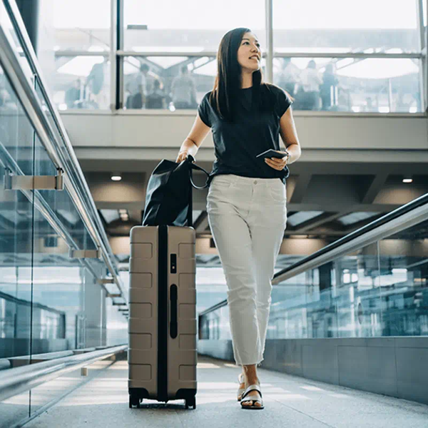 женщина идет по траволатору в аэропорту с багажом