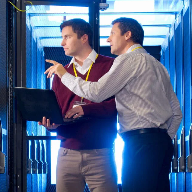 uomo con laptop e uomo che indica un server nella sala server