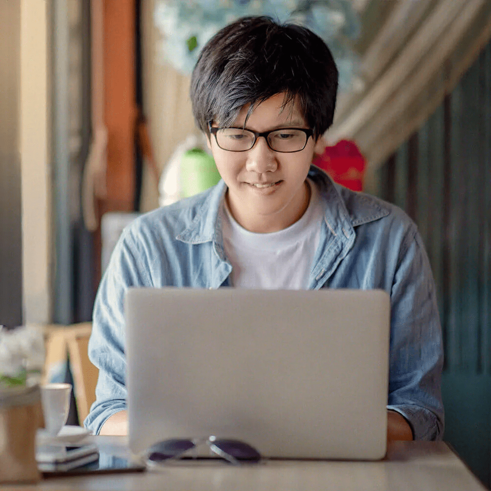 pessoa sorridente sentada em frente ao laptop