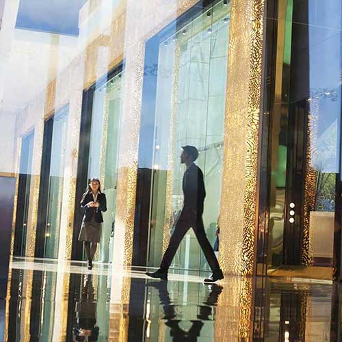 pessoas andando na frente do prédio de vidro