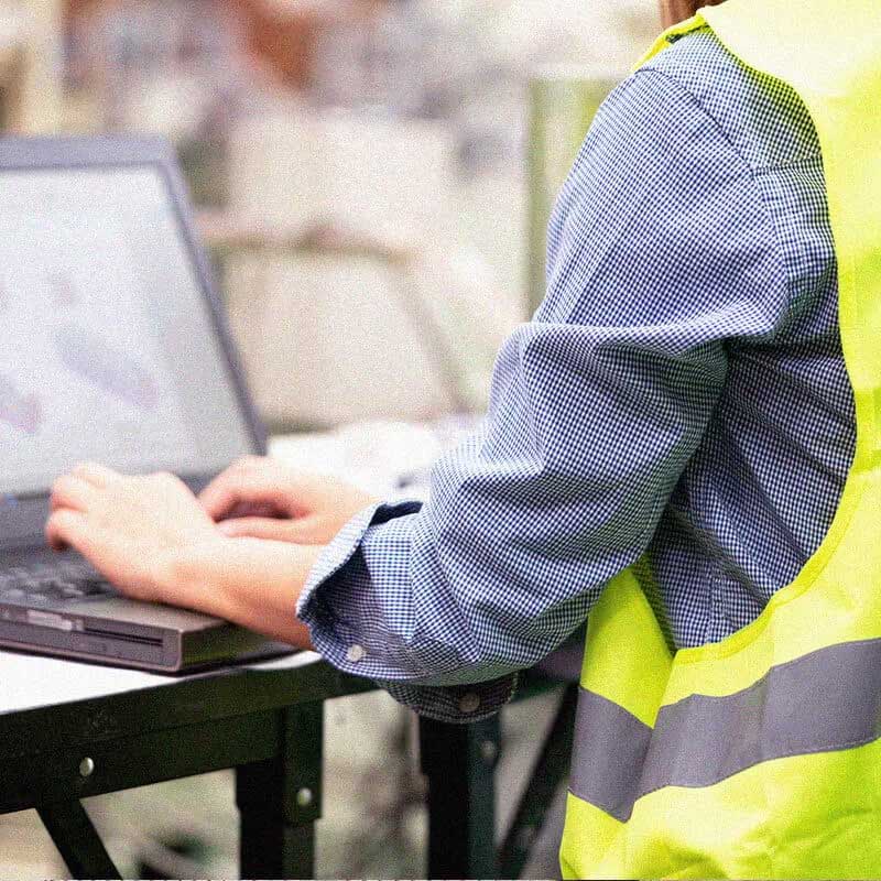 man typing on laptop in a warehouse