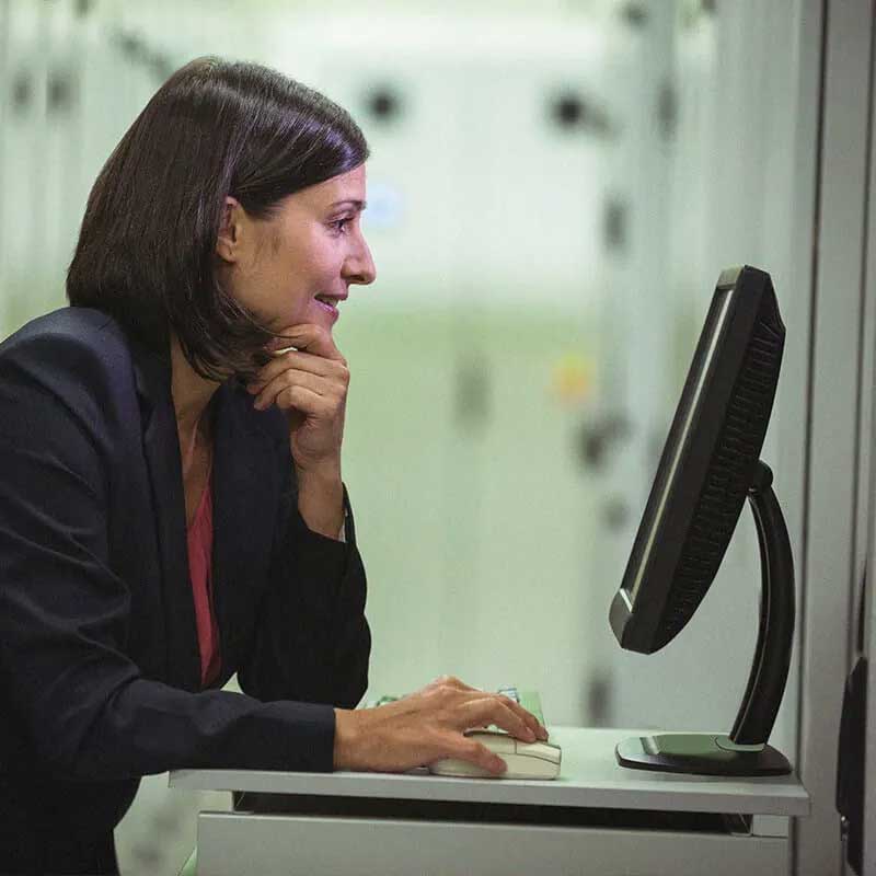 책상에 앉아 데스크탑 컴퓨터 화면을 보고 있는 여성