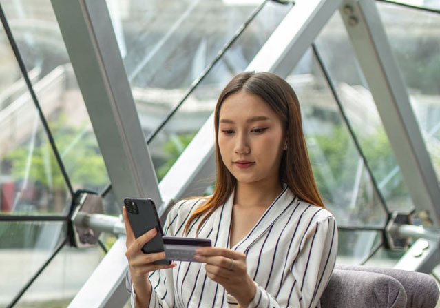 woman looking at phone and credit card