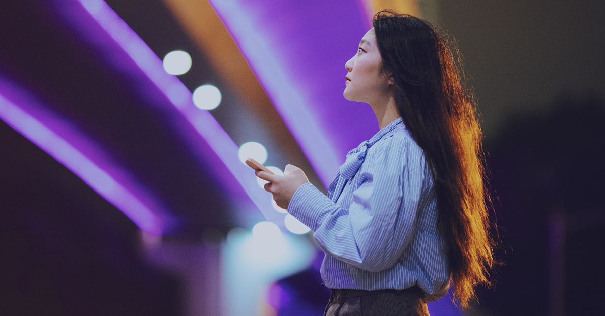 person holding a smartphone under purple LED lights at night, symbolizing secure digital communication and encryption in a modern connected environment.