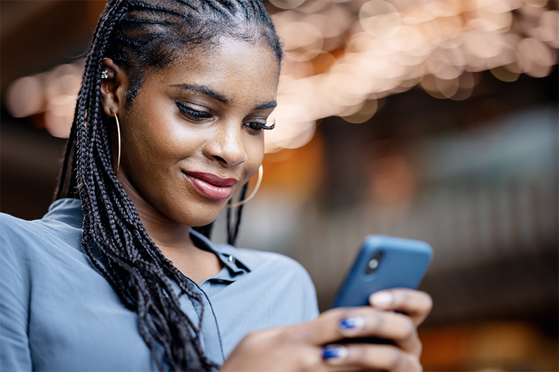 Personne tenant un smartphone et se tenant devant un arrière-plan flou