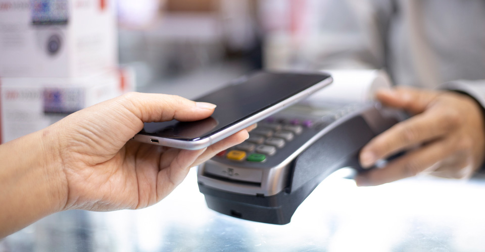 close up of hand using mobile device to pay at a card reader