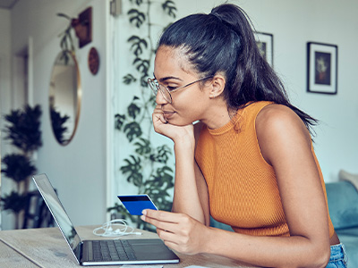 Person holding a credit card while using a laptop