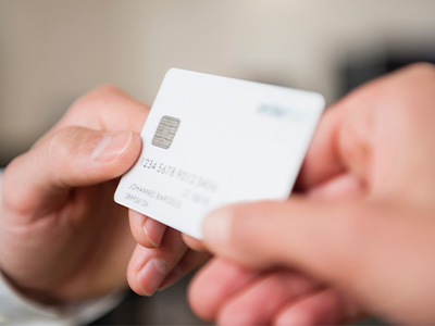Close‑up of one person handing a credit card to another