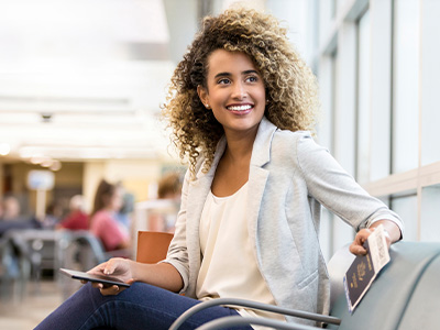 Person seated in an airport holding a passport and mobile device
