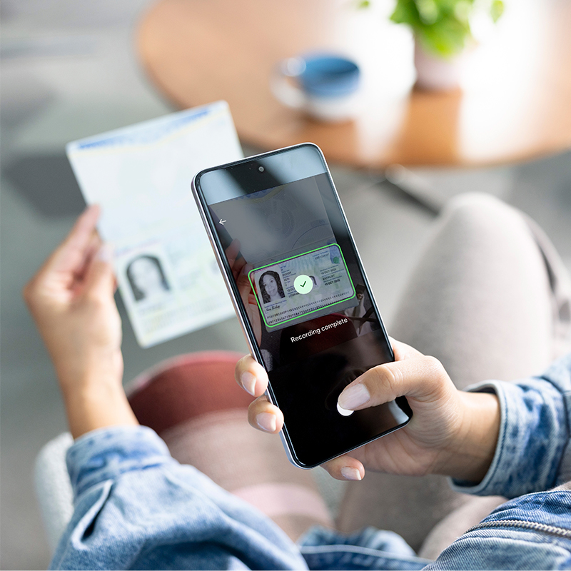 A person uses a smartphone to scan a government-issued ID card