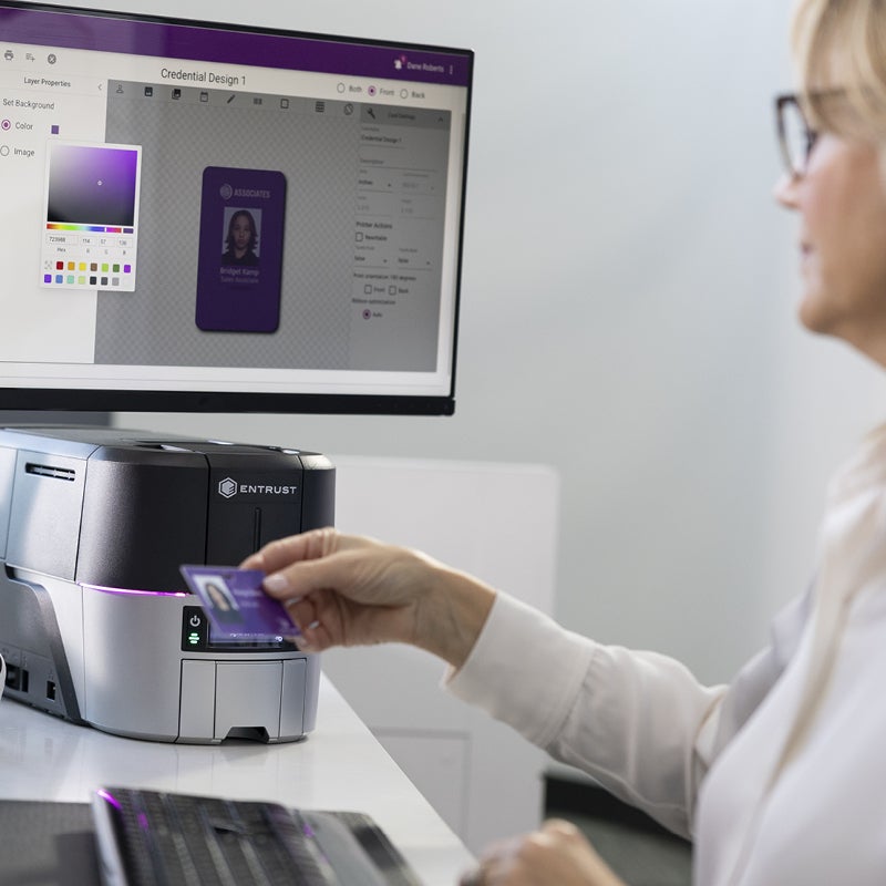 Person using card printer while designing an ID on a computer screen