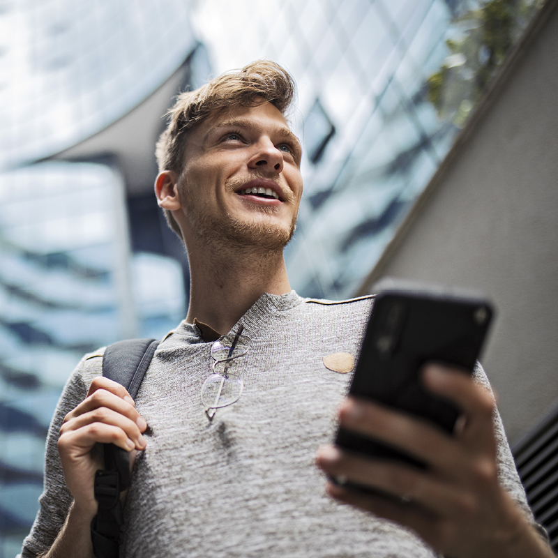 Person holding smartphone outdoors near modern buildings
