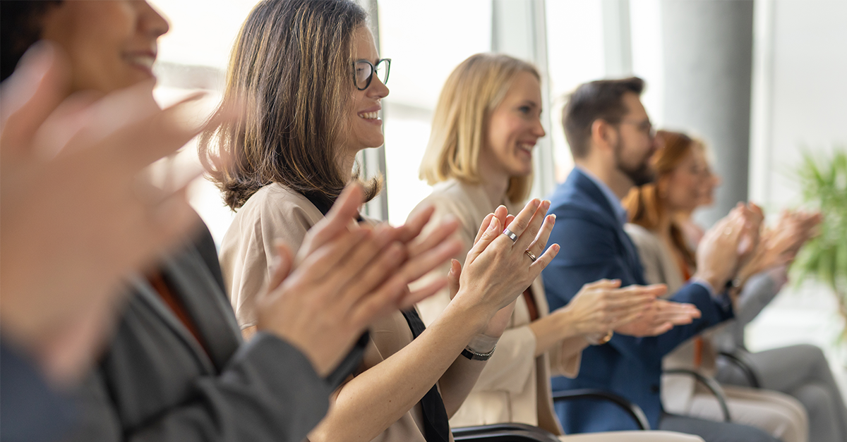 people sitting in a row smiling and clapping