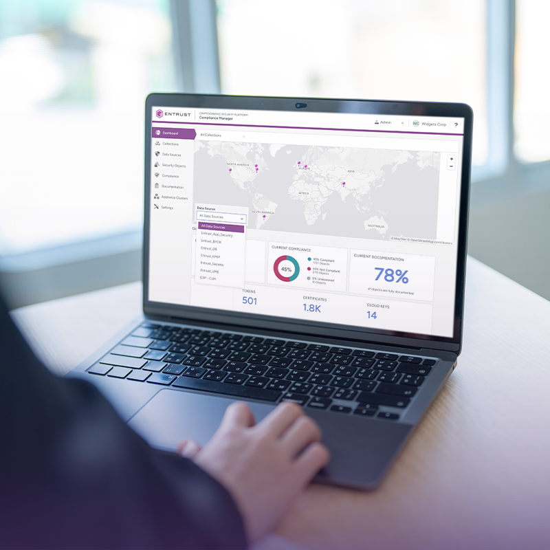 Person using a laptop displaying Entrust compliance dashboard with global map and metrics