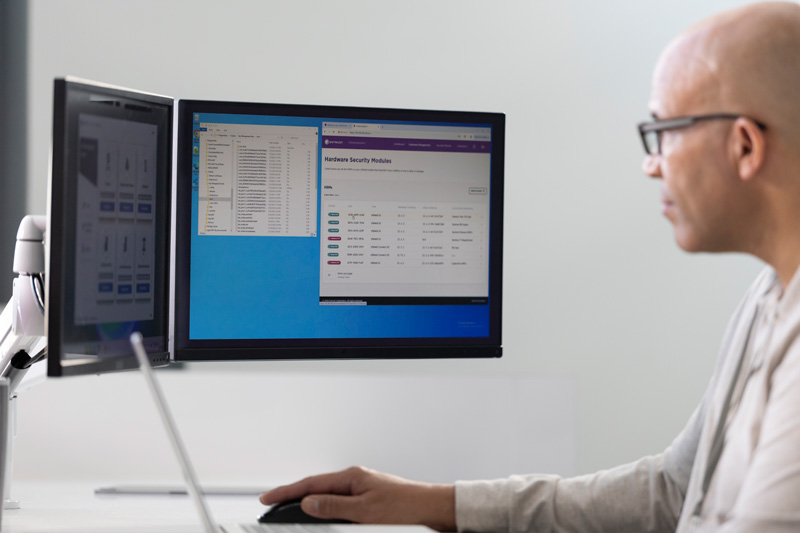 Person working at a computer with dual monitors displaying security management software