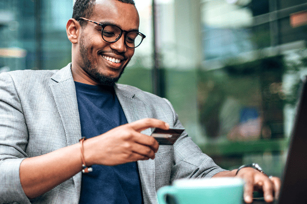 man holding credit card outside at laptop
