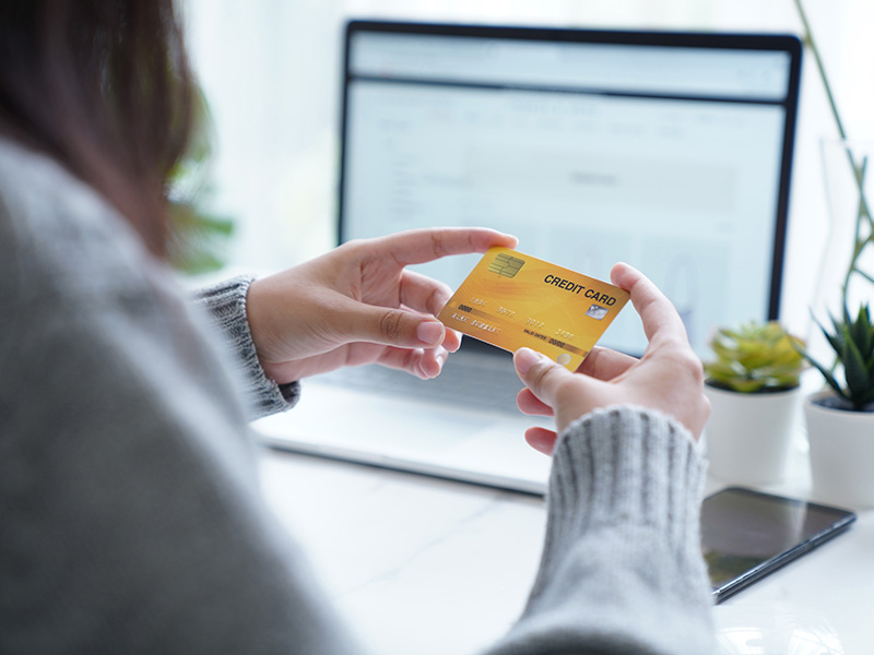 Person holding a credit card in front of a laptop