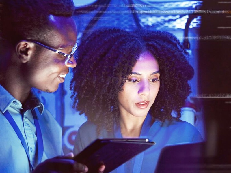 Two people looking over a tablet and computer screen