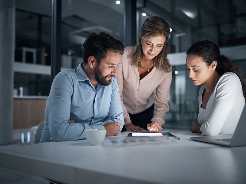 A group of people collaborating at a desk looking at a tablet