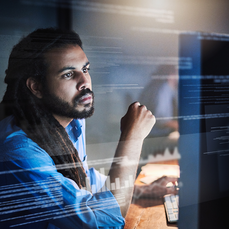 Person working at a computer with digital code and data graphics overlaid on the screen
