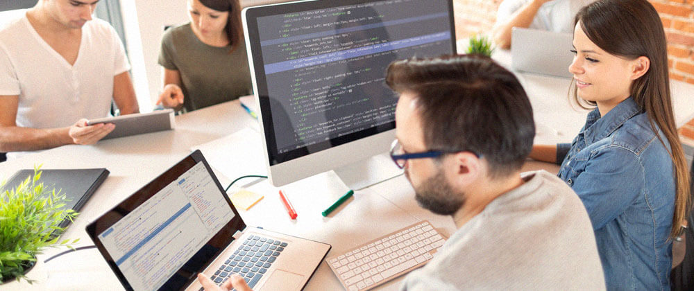 people working around table coding using laptop