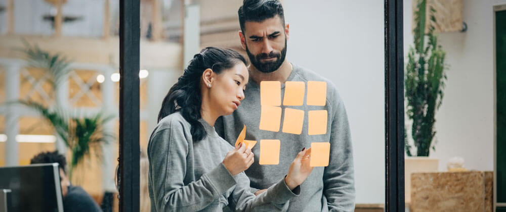 man and woman using post it notes on window