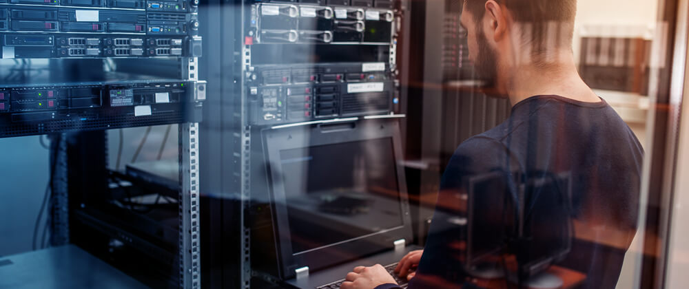 man on laptop in server room
